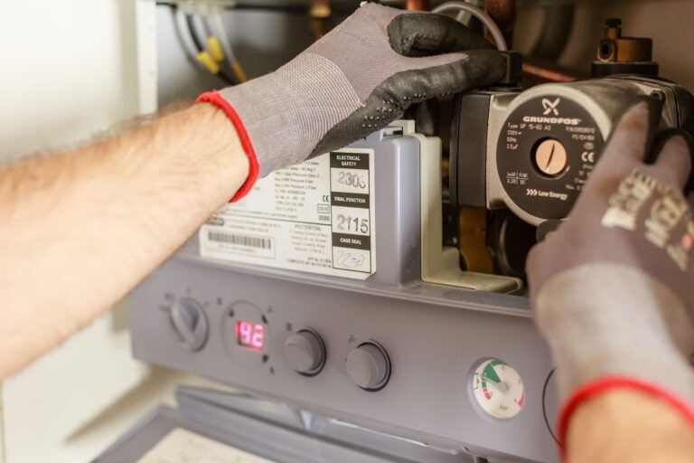Heating engineer working inside an open boiler casing near the pump and pressure gauge